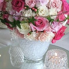 a vase filled with pink and white flowers sitting on top of a table next to a pair of silver shoes