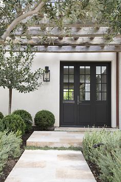 a black front door and some bushes