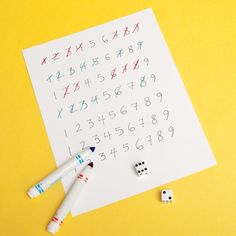 a sheet of paper with numbers and two dices next to it on a yellow surface