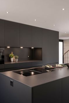 a modern kitchen with black cabinets and counter tops, along with an island in the middle