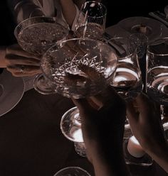 two hands holding wine glasses over a table