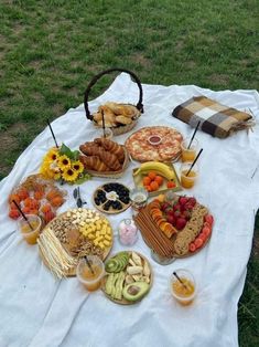 a table full of food and drinks on a blanket in the middle of a field