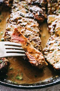 a fork in a skillet with steak and broccoli on it, ready to be eaten