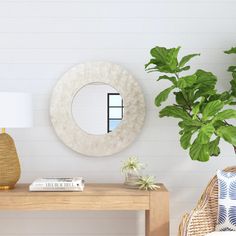 a living room with a table, mirror and potted plant