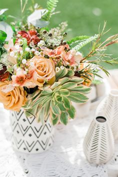 a white vase filled with lots of flowers on top of a table