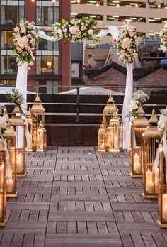 an outdoor wedding setup with lanterns and flowers on the aisle, along with candles in vases