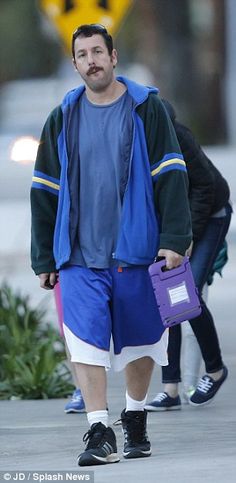 a man walking down the street in shorts and a blue shirt with a purple bag