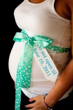 a pregnant woman wearing a green and white polka dot belt with a tag that says so cute