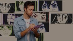 a man standing in front of a wall with anime faces on it and looking at his tablet