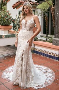 a woman in a white wedding dress standing on a tile floor next to a building