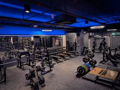 a gym with rows of exercise equipment and blue lights on the ceiling is lit by recessed lighting