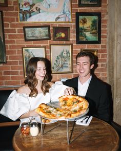 a man and woman sitting at a table with a pizza