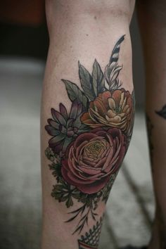 a close up of a person's legs with flowers and feathers tattooed on them