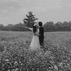 two people standing in a field with flowers