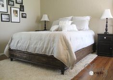 a bedroom with white bedding and pictures on the wall