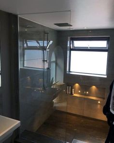 a bathroom with a walk in shower next to a sink and toilet under a window