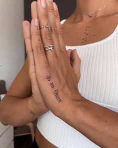 a woman in white shirt holding her hands together with tattoos on both sides of her body