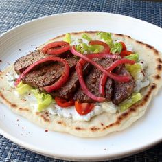 a white plate topped with meat and veggies on top of a blue place mat