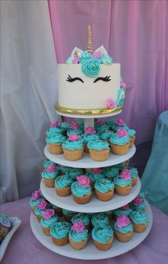 a three tiered cake with blue frosting and pink cupcakes