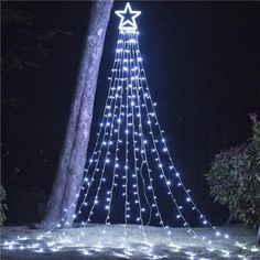 a lighted christmas tree in the middle of a park at night with stars on it