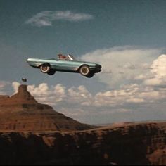 an old car flying in the sky over a mountain