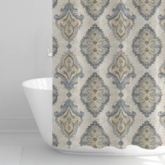 a bath tub sitting next to a shower curtain covered in a blue and beige pattern