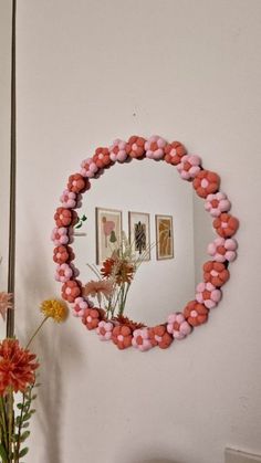 a mirror that is hanging on the wall next to a vase with flowers in it