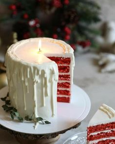 a slice of red velvet cake on a plate with a lit candle in the middle