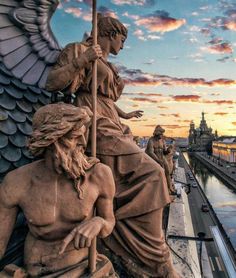 statues on the side of a building with a sunset in the background