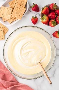 a bowl of dip surrounded by strawberries and crackers