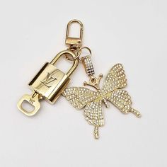 a gold key chain with a butterfly shaped lock on it's side and the letter k in the middle