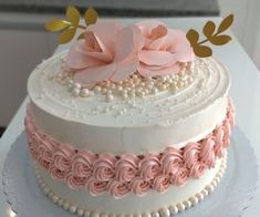 a three layer cake decorated with pink flowers and pearls