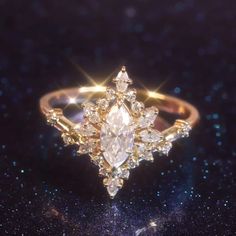 a gold ring with an intricately shaped diamond surrounded by smaller diamonds on a black background