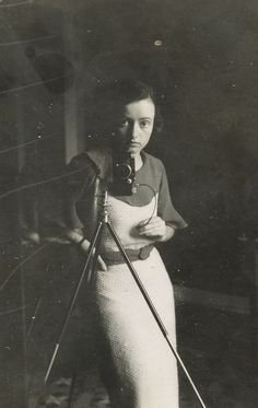 an old black and white photo of a woman holding a camera