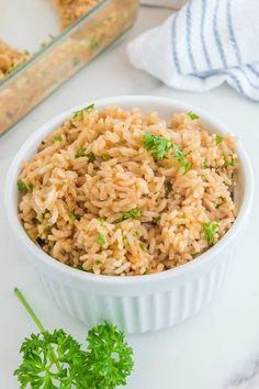 a white bowl filled with rice and parsley on top of a marble countertop