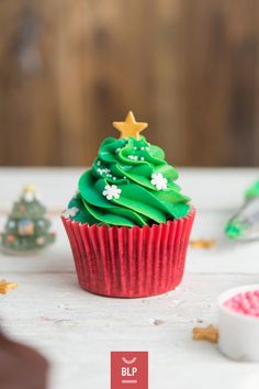 a cupcake decorated with green frosting and a christmas tree on top is shown