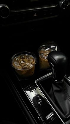 the interior of a car with two cups of iced coffee and an automatic gear lever