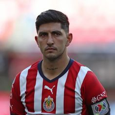 a close up of a soccer player wearing a red and white striped shirt with tattoos on his arm