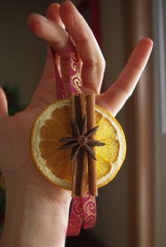 a person holding an orange and cinnamon stick in their hand with star anise on top