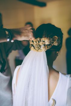 a woman wearing a veil and a gold crown on her head is getting ready to go into the wedding ceremony