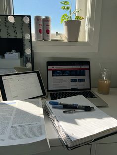 a laptop computer sitting on top of a desk next to a notebook