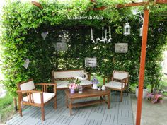 an outdoor seating area with wooden furniture and greenery on the wall behind it,