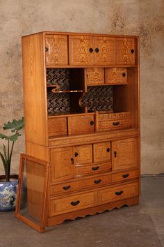 an old wooden dresser with drawers next to a potted plant