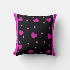 a black pillow with pink hearts on it