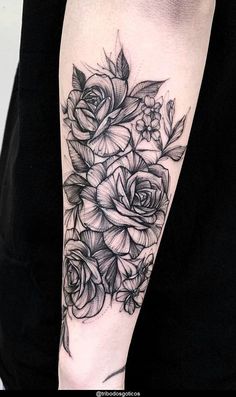 a black and white rose tattoo on the right arm, with flowers in blooming around it