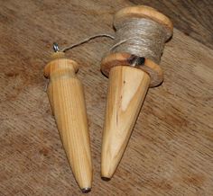 two wooden spools with twine attached to them on a wood table top