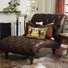 a brown leather chaise lounge chair with deer pillows on it in front of a fireplace