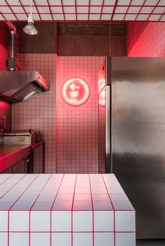 a red and white tiled kitchen with stainless steel appliances