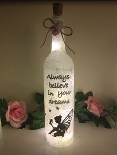 a bottle that has some writing on it with flowers in the background and lights inside