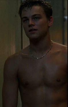 shirtless young man with no shirt on standing in front of a door and looking at the camera